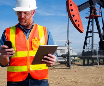 Oil Engineer with Tablet Computer and Pumpjack